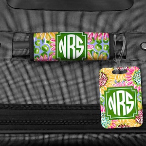 May include: A luggage tag and luggage strap with a sunflower pattern and the monogram "NRS" in white letters on a green circle. The tag and strap are both made of a durable material and are perfect for adding a personal touch to your luggage.