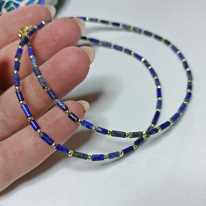 May include: A double-strand necklace made of small, rectangular lapis lazuli beads separated by gold spacers.