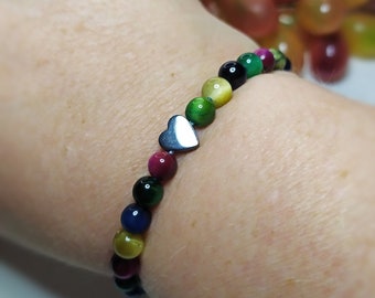 May include: A rainbow colored beaded bracelet with a silver heart charm. The beads are made of tiger's eye, lapis lazuli, and red jasper.