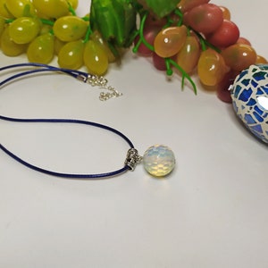 May include: A blue cord necklace with a silver clasp and a white opal pendant.