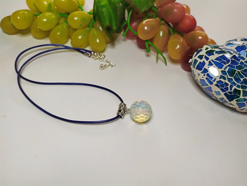 May include: A blue cord necklace with a silver clasp and a white opal pendant.