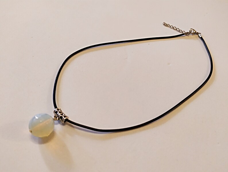 May include: A white opal pendant necklace with a black leather cord and silver clasp.
