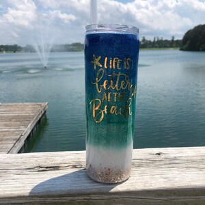 May include: A blue, green, and white glitter tumbler with a gold glitter starfish and the text "Life is better at the beach".