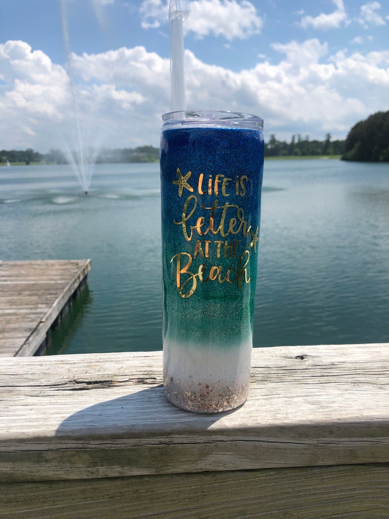 May include: A blue, green, and white glitter tumbler with a gold glitter starfish and the text "Life is better at the beach".