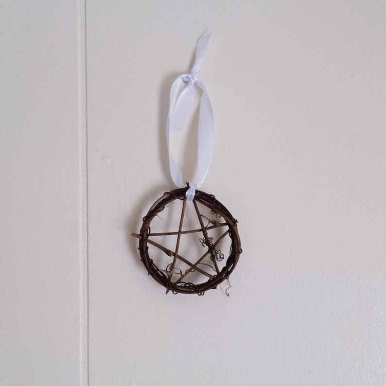 woven grapevine with ribbon tied on it to create a pentacle ornament