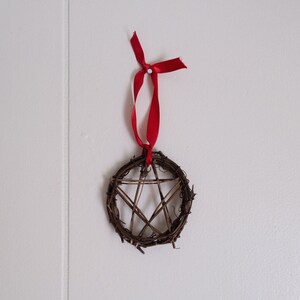 woven grapevine with ribbon tied on it to create a pentacle ornament