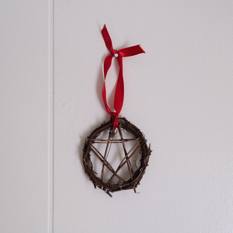 woven grapevine with ribbon tied on it to create a pentacle ornament