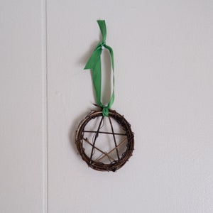 woven grapevine with ribbon tied on it to create a pentacle ornament