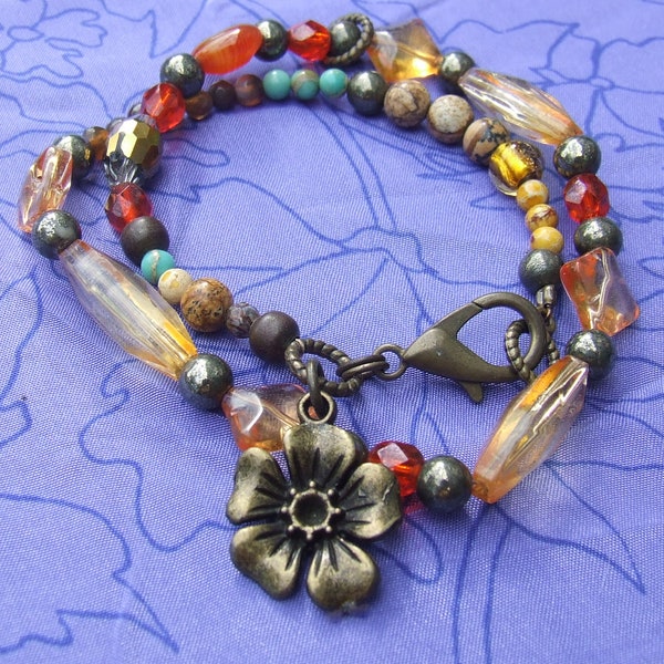 Double wrap vintage style gemstone beaded bracelet finished with antique bronze findings, and flower charm. Fits 7inch wrist.