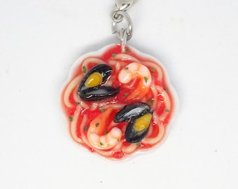 May include: A white ceramic charm featuring a red sauce spaghetti dish with shrimp and mussels. The charm is attached to a silver metal lobster clasp.
