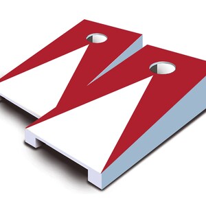 May include: Two red and white cornhole boards with a triangular design and a hole in the center of each board.