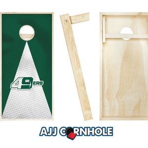 Puede incluir: Un juego de dos tablas de cornhole de madera con un dise&ntilde;o de los San Francisco 49ers en verde y blanco en un lado. El otro lado es de madera natural. Las tablas est&aacute;n listas para jugar con las patas en su lugar.