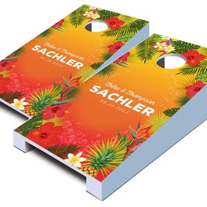 May include: Two orange and yellow tropical themed cornhole boards with the text "Chloe & Thompson Sachler 08.10.2023" printed on them.