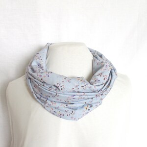 Könnte beinhalten: Ein hellblauer Infinity-Schal mit Blumenmuster. Der Schal ist aus einem weichen, bequemen Stoff gefertigt und perfekt, um jedem Outfit einen Hauch von Stil zu verleihen.