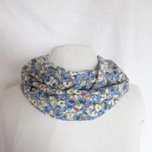 Könnte beinhalten: Ein blauer und weißer floral bedruckter Infinity-Schal. Der Schal ist aus einem weichen, leichten Stoff gefertigt und perfekt, um jedem Outfit einen Hauch von Stil zu verleihen.