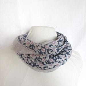 May include: A grey and white floral infinity scarf. The scarf is made of a soft, comfortable fabric and is perfect for adding a touch of style to any outfit.