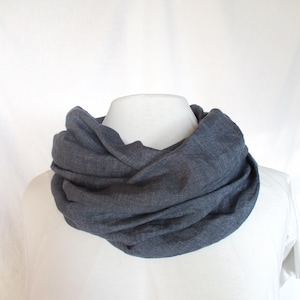 May include: A dark grey infinity scarf made of a soft, textured fabric. The scarf is folded and draped around a mannequin's neck.