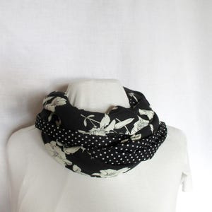 May include: A black and white floral patterned infinity scarf with a polka dot pattern on the underside.
