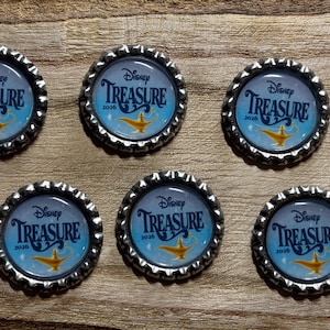 May include: Six circular bottle caps with a silver serrated edge. Each cap features a light blue background with the text Disney TREASURE 2026 in dark blue lettering and a graphic illustration of a gold magic lamp centered at the bottom.