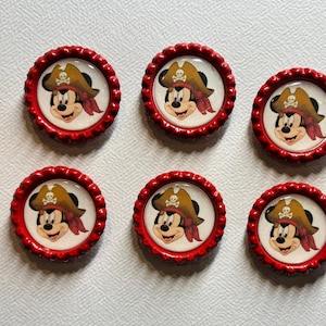 May include: Six red bottle caps with a white background and a picture of Mickey Mouse dressed as a pirate. Mickey Mouse is wearing a brown pirate hat with a skull and crossbones on it and a red bandana.