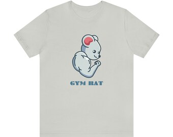 Könnte beinhalten: Ein hellgraues T-Shirt mit einem Cartoon-Bild einer muskulösen Maus, die ihren Bizeps beugt. Der Text "GYM RAT" ist unter dem Bild aufgedruckt.