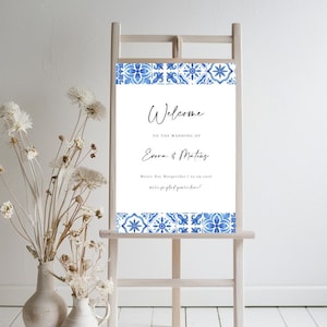 Könnte beinhalten: Willkommensschild mit einem blauen und weißen Fliesenmuster als Rahmen. Das Schild lautet "Willkommen zur Hochzeit von Emma und Mattias".