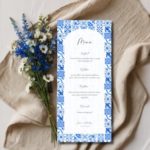 Puede incluir: Un menú de boda azul y blanco con un borde decorativo de azulejos azules y blancos. El menú enumera los platos: para empezar, para seguir y para terminar. El menú está titulado "Menú" e incluye los nombres "Emre & Melisa" en la parte inferior.