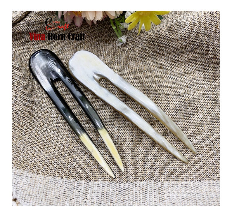 Puede incluir: Dos horquillas para el cabello hechas de cuerno. Una es negra y la otra blanquecina. Ambas tienen un dise&ntilde;o de dos puntas con un acabado liso y pulido. Las puntas de la horquilla negra son de color amarillo claro. Miden unos 15 cm.
