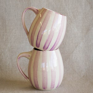 A stack of handmade mugs with a glossy glaze and hand painted purple stripes