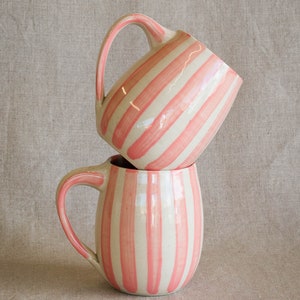 A stack of two handmade mugs with pink painted vertical stripes