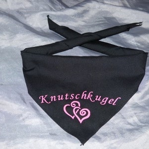 Könnte beinhalten: Schwarzes Halstuch mit dem Text "Knutschkugel" in rosa Schrift und zwei rosa Herzen. Das Halstuch ist dreieckig gefaltet und die Enden sind zusammengebunden.