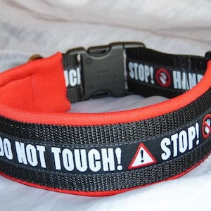 Könnte beinhalten: Ein schwarzes und rotes Hundehalsband mit dem Text "NICHT ANFASSEN! STOP!" und einem roten Handabdruck-Symbol. Das Halsband ist mit rotem Material gepolstert.