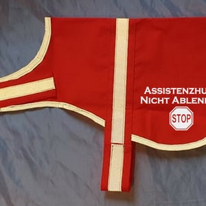 May include: Red dog vest with white reflective trim and the text "ASSISTENZHUND NICHT ABLENKEN" and a red stop sign.