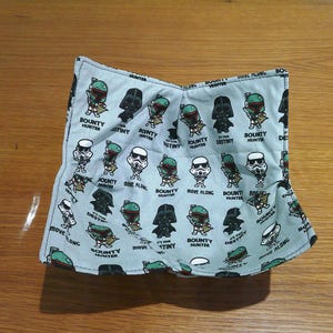 May include: A blue fabric square with a repeating pattern of Star Wars characters, including Boba Fett, Darth Vader, and a green alien. The text "Bounty Hunter" and "It's Your Destiny" are repeated throughout the pattern.