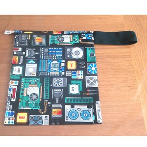 May include: A black fabric bag with a repeating pattern of computer components in green, blue, and yellow. The bag has a black handle and a small tag with text. The design includes CPUs, circuit boards, and hard drives.