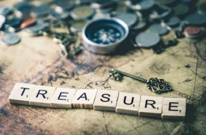 May include: A vintage treasure map with a compass, a key, and the word "TREASURE" spelled out in wooden letter tiles.