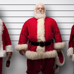 May include: Three men dressed as Santa Claus stand in a police lineup. The man on the left is holding a beer bottle and a cigarette. The man in the middle is standing with his hands on his hips. The man on the right is standing with his hands in his pockets.