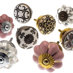 Può includere: Assortimento di otto pomelli decorativi per armadi in vari stili. I pomelli sono in ceramica rosa, bianca e nera con accenti dorati e argentati. Alcuni pomelli hanno un design floreale, mentre altri hanno motivi geometrici.