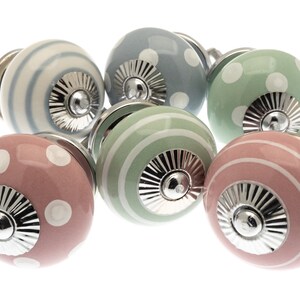 May include: Six decorative cabinet knobs in pastel shades. The knobs have stripe and polka dot patterns, with a silver-coloured base. Colours include pink, blue, green, and white. These knobs are ideal for furniture.
