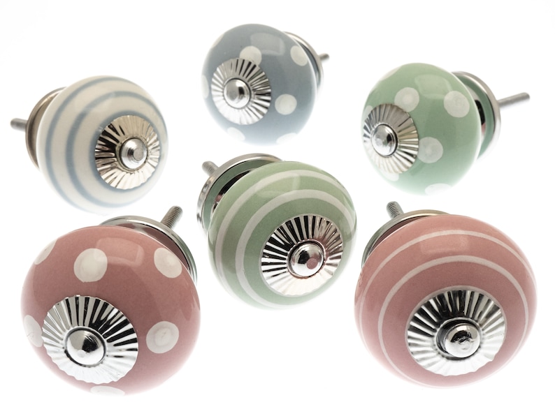 May include: Six ceramic cabinet knobs in pastel shades of pink, blue, and green. Each knob has a silver base and is decorated with either polka dots or stripes. These knobs are perfect for adding a touch of charm to furniture, and are measured in centimetres.