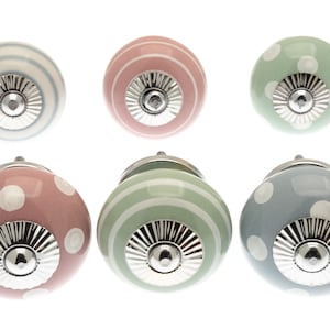 May include: Six ceramic cabinet knobs in pastel shades of pink, green, and blue. Some knobs are decorated with white polka dots, others with stripes. Each knob has a silver metal base.