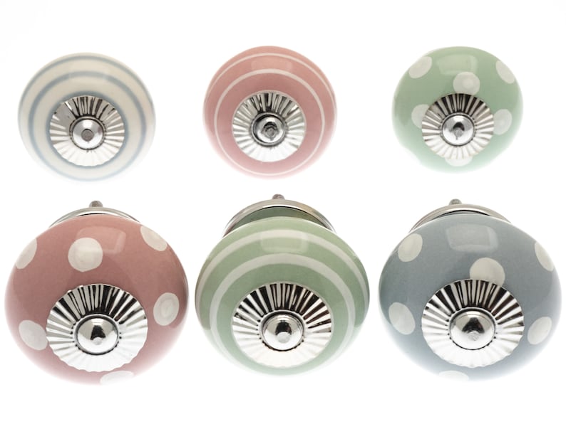 May include: Six ceramic cabinet knobs in pastel shades of pink, green, and blue. Some knobs are decorated with white polka dots, others with stripes. Each knob has a silver metal base.
