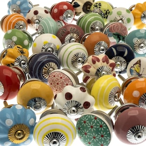 May include: A collection of colorful ceramic cabinet knobs with various patterns, including stripes, polka dots, and floral designs. The knobs feature silver hardware and come in a variety of colors such as blue, orange, yellow, and green.