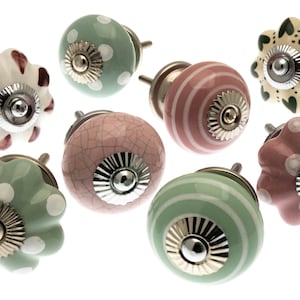 May include: Assortment of eight ceramic cabinet knobs in various colours and patterns. The knobs feature a variety of designs, including polka dots, stripes, and floral motifs. Each knob has a silver metal base.