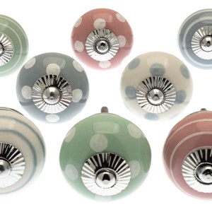 Puede incluir: Conjunto de ocho pomos de armario de cer&aacute;mica con una variedad de colores pastel y patrones, incluyendo lunares, rayas y una combinaci&oacute;n de ambos. Cada pomo tiene una base de metal plateado.