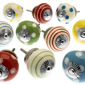 May include: A selection of decorative ceramic cabinet knobs in various colours. The knobs feature patterns such as polka dots and stripes in red, yellow, green, blue, and white. Each knob has a silver-toned metal base and screw.