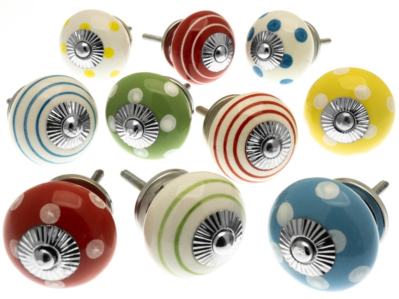 May include: A selection of decorative ceramic cabinet knobs in various colours. The knobs feature patterns such as polka dots and stripes in red, yellow, green, blue, and white. Each knob has a silver-toned metal base and screw.