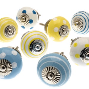 May include: Eight ceramic cabinet knobs in assorted colours and patterns. Designs include yellow with white polka dots, blue with white polka dots, and white with blue stripes. Each knob has a silver metal base.