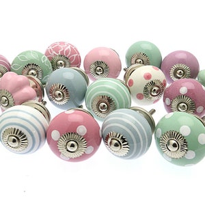 May include: A collection of 16 ceramic cabinet knobs in pastel colors with various patterns, including polka dots, stripes, and floral designs. The knobs have a silver finish.