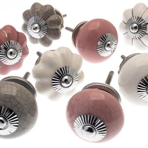May include: Assortment of eight ceramic cabinet knobs in various colours and patterns. The knobs feature a raised, textured design and a silver metal base.